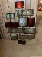 Front view of metal wall art with multiple textured rectangular panels, showing scratches and overall condition.