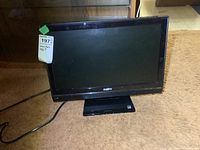 Front view of a black Sanyo 19-inch LCD television with stand, showing the screen and power cord on a brown carpet.