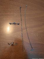 Photo of two brooches and a sterling silver chain with pendant on wooden background