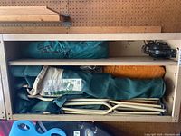 View of shelves showing packed camping tent, two folding chairs, and tarp/ground cover rolled in bags