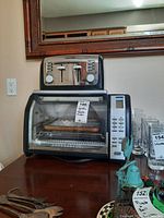 Front view of Black & Decker two-slice toaster placed on top of a Black & Decker digital toaster oven. Both appliances on a wooden surface.