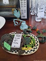 Full view of the bell, trivets, and rooster key holders on a wooden surface