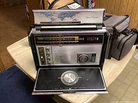 Front view of Zenith Trans-Oceanic radio showing tuning dials, speaker grill, and pull-out panel with compass.