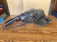 Electric sander viewed from above showing the label and handle with side grip, power cord coiled around the tool.