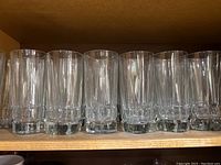22 clear Libbey water glasses lined up on shelf, showing consistency in size and shape, solid glass bases visible.