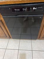 Front view of black KitchenAid dishwasher integrated into kitchen cabinetry showing control panel and door.