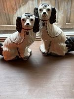 Pair of detailed ceramic English dog figurines, black and white, on a wooden surface.