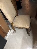 Side angle view of vanity chair showing ornate wood frame and damask fabric upholstery on seat and backrest