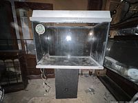 Front view of the glass reptile aquarium with white light fixture on top and black base, showing moderate dust and usage.