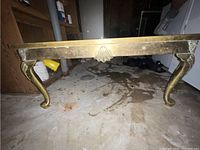 Full side view of the solid brass table showing cabriole legs and decorative apron with shell detail