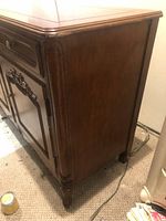 Side view showing the carved legs and sides of the cherry berry wood buffet with minor surface wear.