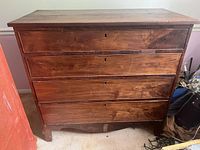 Front view of vintage wooden chest showing four drawers with keyholes and wood grain.
