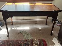 Front view of wooden desk showcasing two drawers and straight legs, surface has scratches and wear.