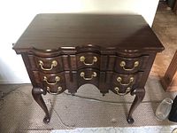 Front view of the solid wood side table showing the drawers and brass handles with scratches on surface.