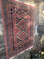 Full view of the Oriental rug laid on a wooden surface showing the entire rectangular shape and overall design.