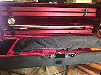 Opened hard shell case interior showing bow and hygrometer mounted on lid