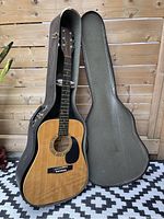Full view of acoustic guitar in open molded case, showing guitar body and case interior