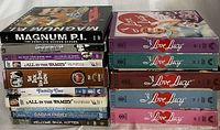 Full collection of vintage TV series DVD sets stacked in two piles showing titles and seasons