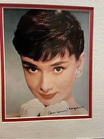 Front view of matted color headshot photograph showing Audrey Hepburn’s face and signature.