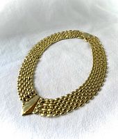 Full view of the vintage gold tone panther link necklace laid flat showing seven rows of linked chains and the pointed centerpiece.