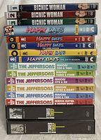 Stacked DVD series sets showing titles and seasons, including Bionic Woman seasons 1-3, Happy Days seasons 1-6, The Jeffersons seasons 1-11, and It Takes a Thief volumes 1-2.