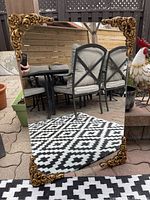 Full view of the rectangular mirror showing golden floral and scroll design ornate corners and the clear reflective quality.