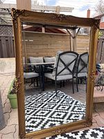 Full view of rectangular mirror leaning outdoors showing black and white patio set reflected