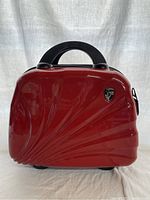 Front view of the red hard case travel bag showing candy apple red finish and Heys logo.