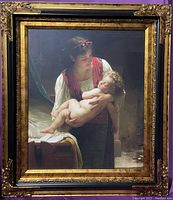 Full view of the painting in black and gold ornate frame showing the mother holding child scene.