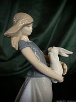 Side view of the porcelain statue showing the girl holding the rabbit with detailed hair and clothing.
