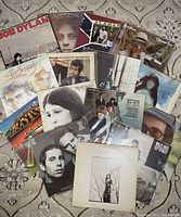 Overview of entire vinyl record lot spread on carpeted floor showing 16 albums with visible artist names and cover art.