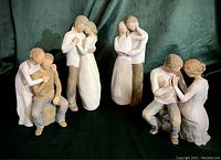 Four Willow Tree figurines displayed on a green background, showing various intimate couple poses
