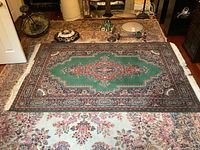 Top view of the Anatolia area rug showing its full design and colors on a floral patterned floor rug beneath.