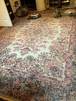 Full view of the handmade wool carpet laid out, visible patterns and overall condition with wear and stains.