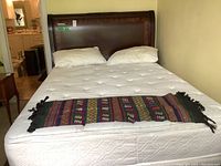 Full view of the wood bed frame with white mattress showing headboard and part of side rails.