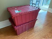 Two red plastic storage containers stacked one on top of the other, showing size and condition from an angle