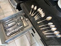 Open drawer with assortment of stainless steel forks, knives and spoons.