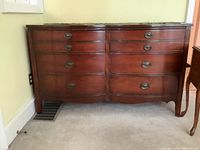 Front view of the wood dresser showing six drawers in two columns with metal oval handles and reddish-brown finish.