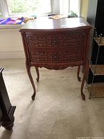 Front view of the two drawer wooden night table showing carved drawer fronts and metal ring pulls.