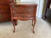 Full view of night table showing two carved drawers, curved design, and four legs.