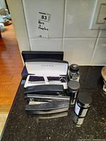 Top-down view of Cross pen in case, two staplers, and three ink bottles on black countertop