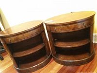 Pair of oval wood side tables showing front view, drawer closed and open shelves