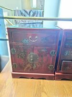 Front view of red painted wood side table showing drawer, doors, brass hardware