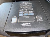 Close-up photo of the control panel of the Bose Wave Radio/CD showing buttons and branding.