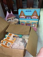 View of Fisher Price dollhouse main parts including boxed additional house pieces and figures.