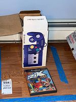 Purple GameCube controller box opened showing controller and SSX Tricky game case on floor