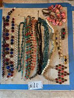 Wide shot showing the full assortment of jewelry, including necklaces, bracelets, and a pin on a flat surface.