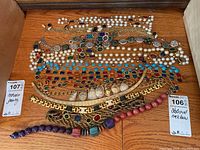 Photo of assorted statement necklaces laid out on wood surface including faux pearls, colorful stones and beaded necklaces
