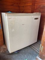 Front view of a white Haier mini fridge showing dirt and usage wear.