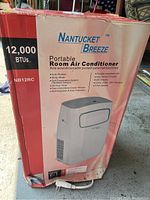 Photo of the original packaging box showing Nantucket Breeze portable air conditioner. Box indicates 12,000 BTU cooling capacity and model NB12RC.